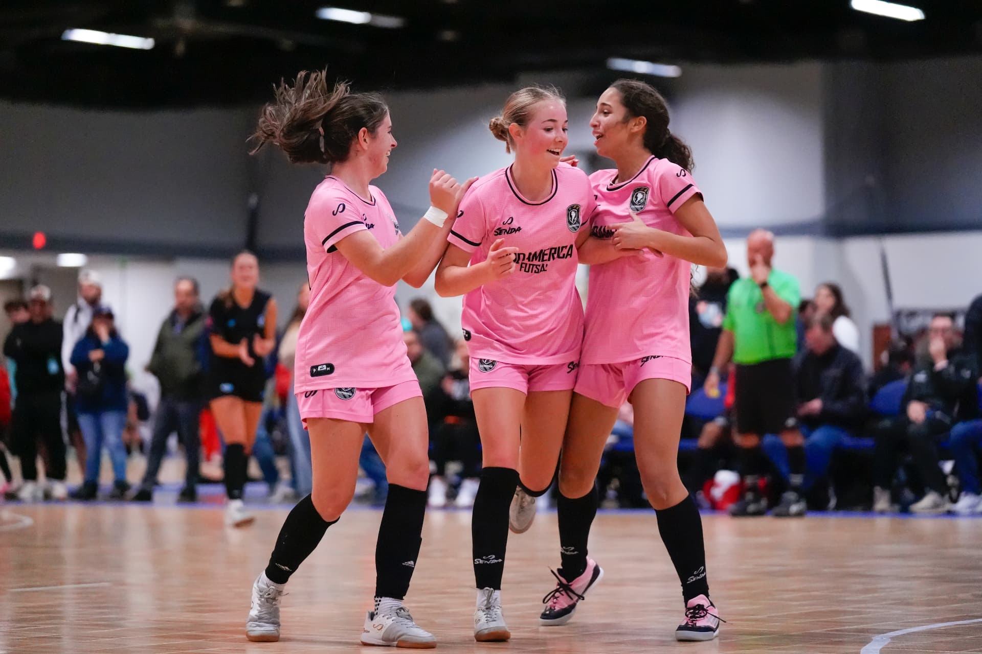 Sudamerica Futsal players celebrating together in pink kits